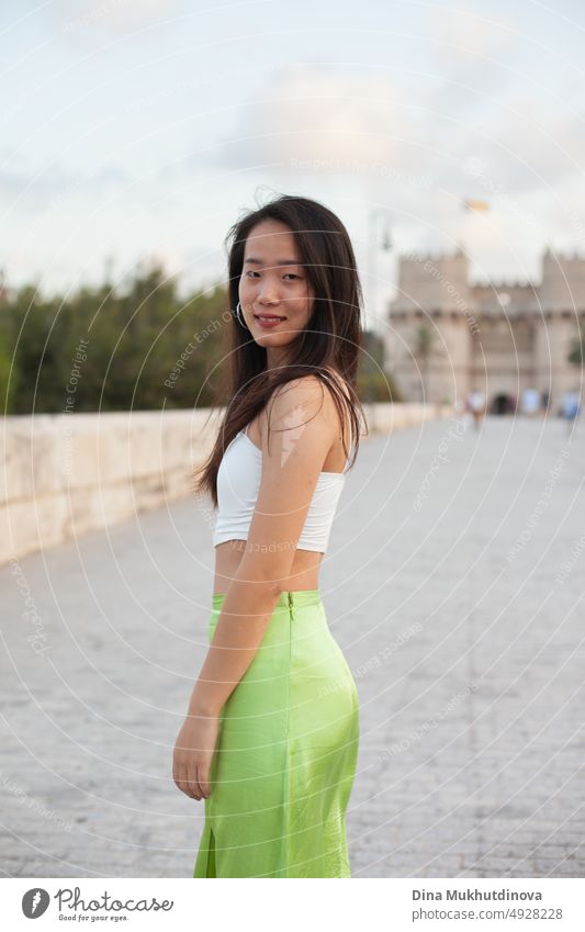 Beautiful young Asian woman walking the street of historic European town. Female tourist from China traveling in Europe, smiling. Exchange student. beautiful