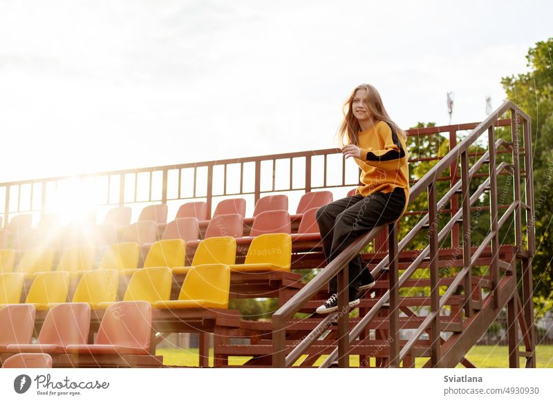 A teenage girl has fun and slides down the railing at the stadium stairs ride beautiful railings cool play teenager staircase childhood lifestyle street fashion