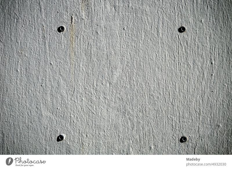 Four boreholes with dowels on gray plaster in the sunshine in Oerlinghausen near Bielefeld on the Hermannsweg in the Teutoburg Forest in East Westphalia-Lippe