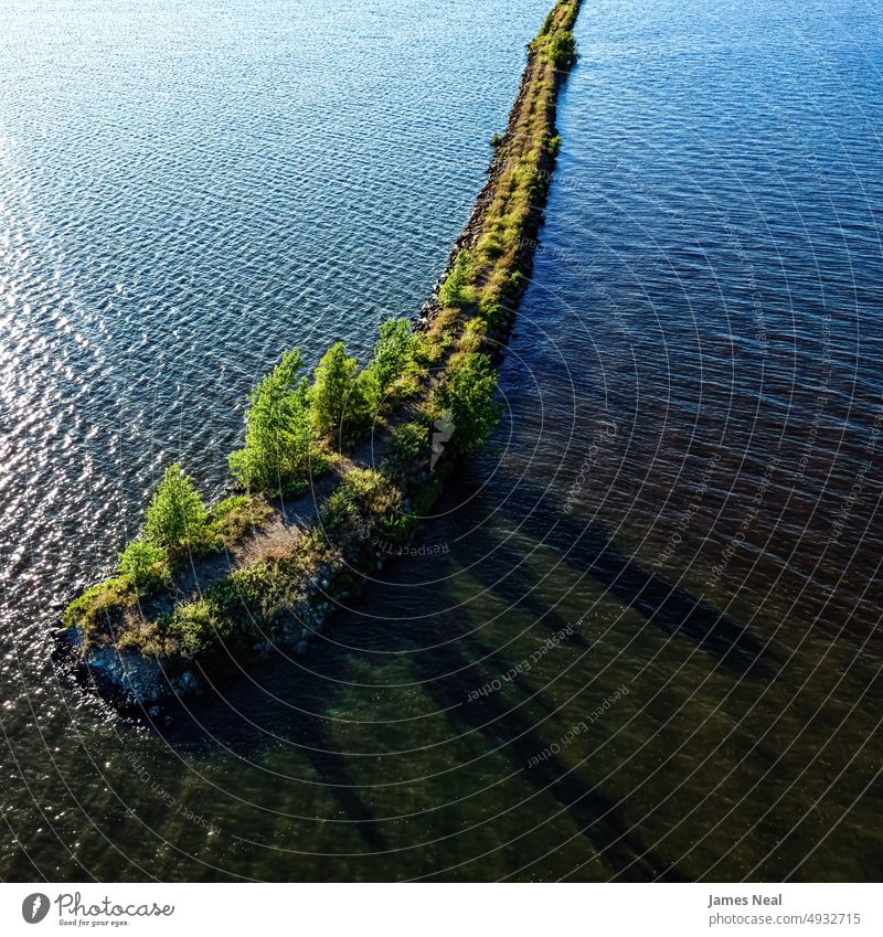 Sun shines brightly over end of the breakwall on Lake Butte des Morts in Oshkosh Wisconsin shoreline sunny fox river jagged nature water day lake background