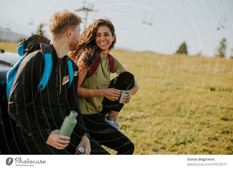 Young couple relaxing on a terrain vehicle hood at countryside adult adventure attractive auto automobile man break calm car caucasian day drink drinking enjoy