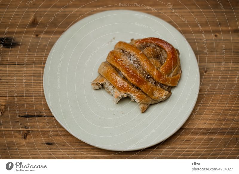 Bitten cardamom snail on a white plate Cardamom snail biscuits Tartlet bitten into Plate pastry Pastry Delicious cute gluten Candy Baked goods Cardamom bun