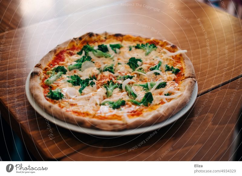 Pizza with broccoli and onions on a plate on a table at Italian restaurant Table Plate Broccoli Vegetable Round Food Lunch Nutrition Dinner Meal Italians Eating