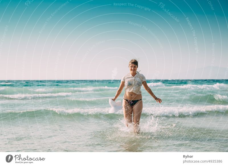 Young Caucasian Lady Woman In Swimsuit And Summer Hat Walking In Sea Water. Vacation On Sea Ocean Beach Aegean Sea Splashes active active lifestyle attractive