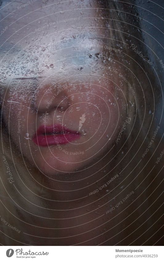 rainy outlook_ young blonde woman behind wet window pane looks outside into the distance during the rain Bad weather dejected sad Grief Drops of water Water