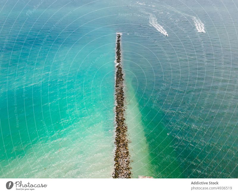 Long breakwater in turquoise ocean on sunny day sea picturesque motorboat seascape idyllic beach rocky float coastline wavy sunlight miami beach florida