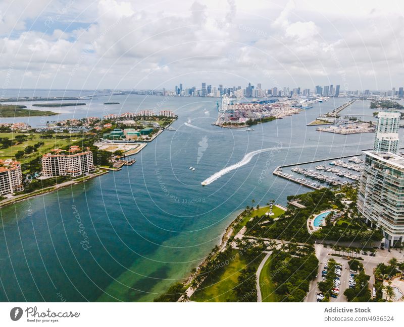 Motorboat floating in ocean near coastal city with modern buildings sea beach cityscape residential district picturesque water cloudy sky vessel resort