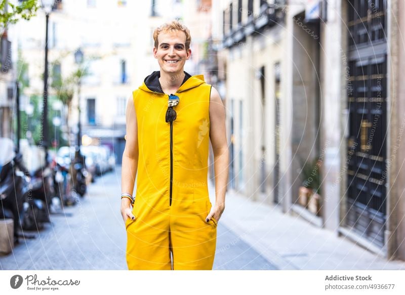 Smiling stylish non binary male on street man style urban pavement cheerful delight transgender confident modern lgbt hands in pocket glad young happy smile