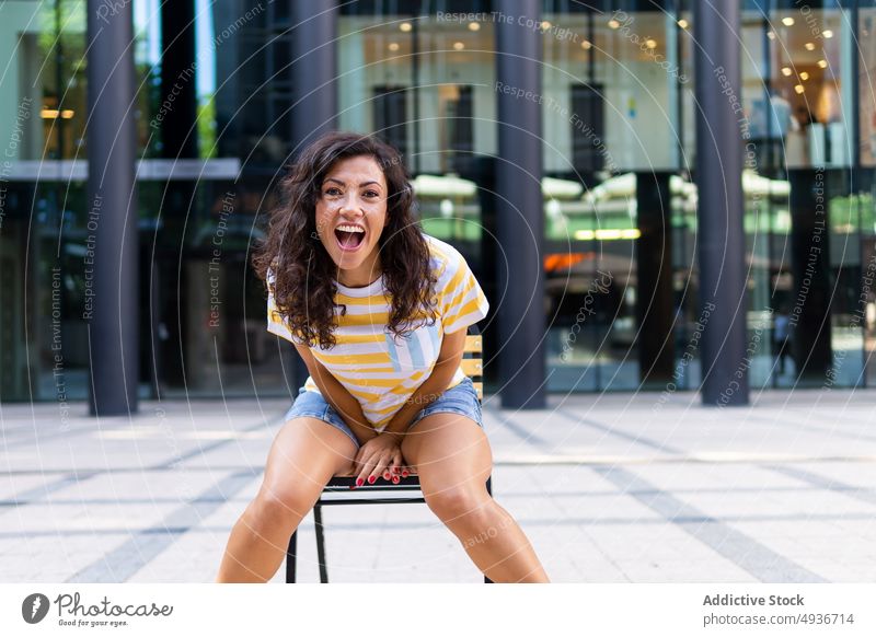 Joyful woman sitting on street near building mouth opened city scream shout yell style happy urban fashion feminine appearance female lady brunette path pathway