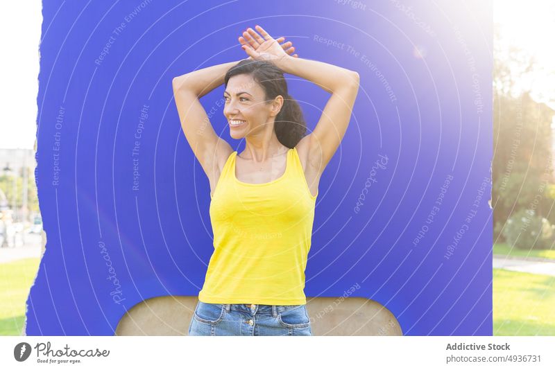 Delighted woman smiling while standing in park with hands on head smile self assured positive portrait happy cheerful delight individuality glad female adult