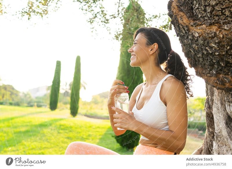 Delighted sportswoman with water in countryside training workout fitness healthy lifestyle break sporty thirst bottle hydrate open appearance beverage plant