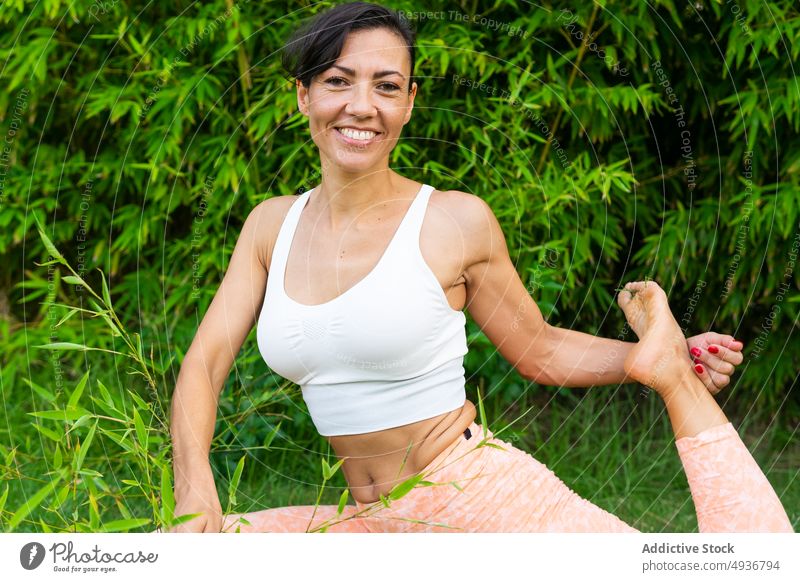 Smiling woman doing asana in park yoga training exercise practice hobby healthy lifestyle smile effort positive glad optimist tree content cheerful sportswear