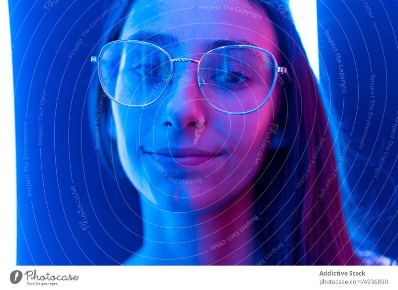 Young woman in nightclub hallway corridor wall blue neon futuristic illuminate colorful female young long hair bright glasses glow modern nightlife luminous