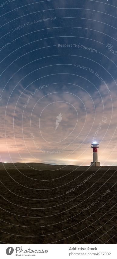 Lighthouse against cloudy sundown sky lighthouse seashore sunset tower navigate seaside guide illuminate twilight dusk ocean evening beacon coast dark beach