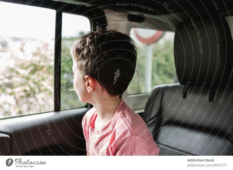 Boy admiring countryside during road trip boy window car admire backseat passenger weekend ride nature childhood lollipop vehicle kid journey summer transport