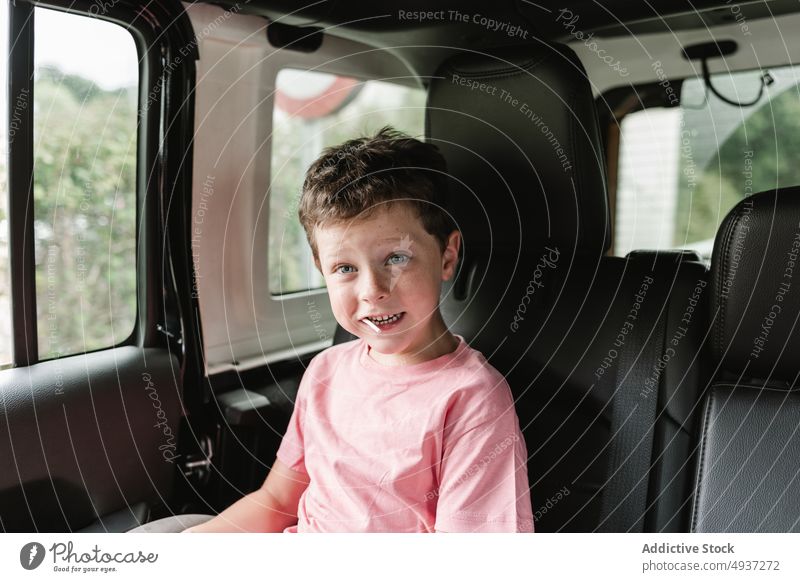 Boy looking at camera during road trip boy window car countryside backseat passenger weekend ride nature childhood lollipop vehicle kid journey summer transport