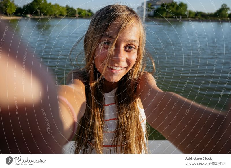 Girl taking selfie on embankment girl kid smartphone smile photography social media waterfront river capture memory moment content happy self portrait seafront