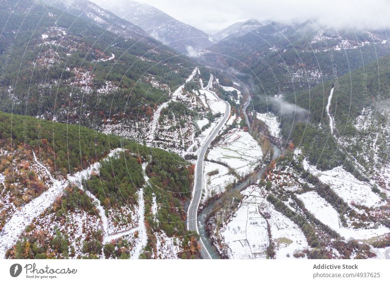 Picturesque mountainous landscape with snowy slopes and narrow river winter road valley ridge fog highland picturesque scenic range scenery peaceful cold mist