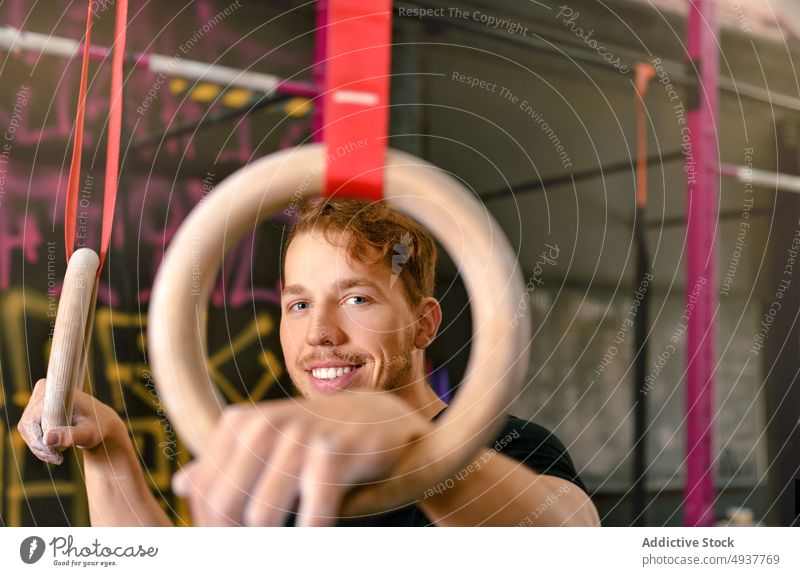 Male athlete preparing to exercise with gymnastic rings sportsman smile prepare ready training happy strong male young glad cheerful power activity energy