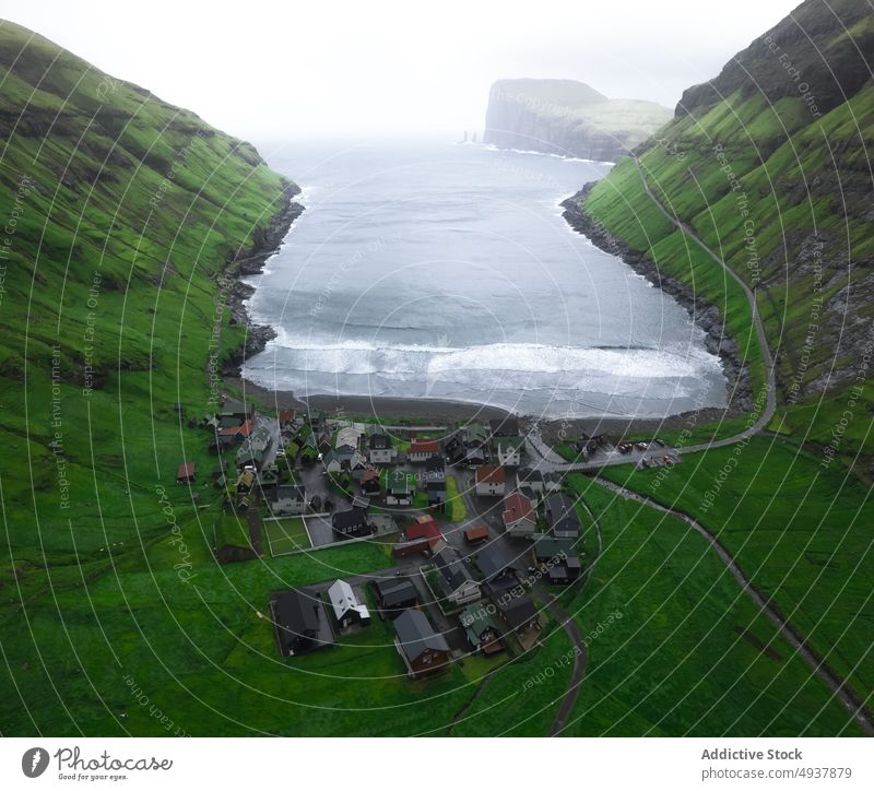 Small village near sea on fjord wave storm weather water seaside marine house faroe islands settlement roll splash green formation daytime scenic waterfront