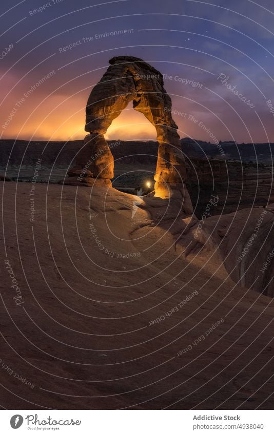 Traveler with flashlight near stone arch against sunset sky traveler formation starry desert illuminate cloudy nature arid arches national park dark night