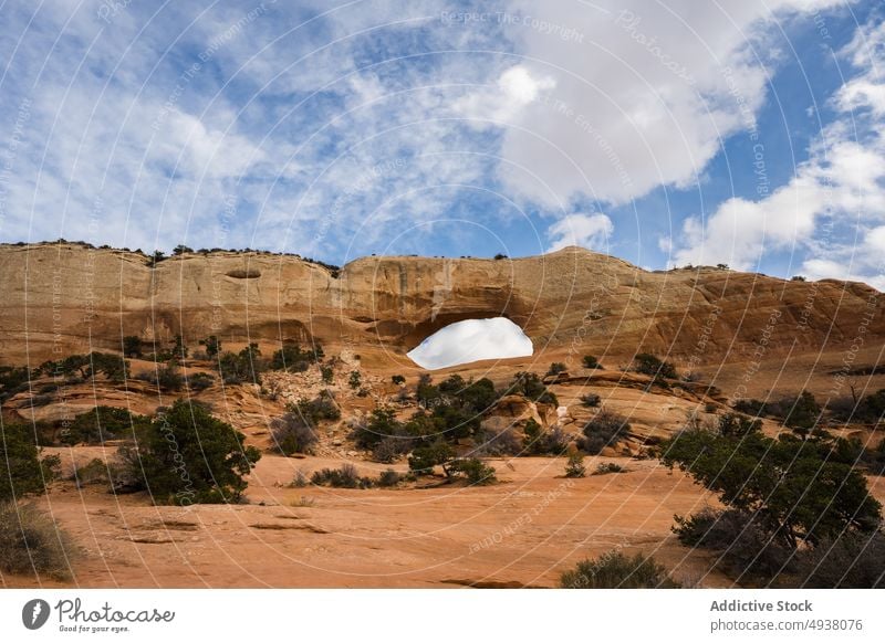 Stone arch in desert on cloudy day arid bush blue sky summer nature stone landmark window arch arches national park moab utah usa united states america shrub