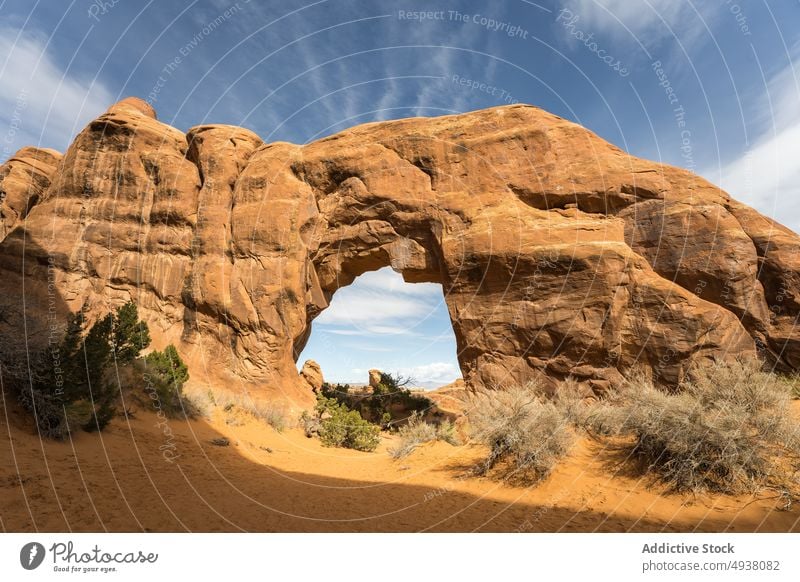 Stone arch in desert on cloudy day arid bush blue sky summer nature stone landmark window arch arches national park moab utah usa united states america shrub