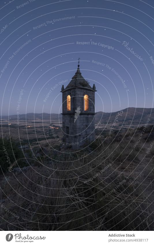 Illuminated bell tower on hill monastery night sky starry countryside illuminate old avila spain ruin remain architecture dark historic evening landmark worship