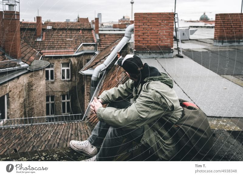 a man with cape sits on a roof and turns away Berlin Middle Roof Man Downtown Berlin Town Capital city Exterior shot Manmade structures Architecture City