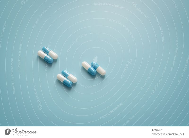 Pairs of white-blue antibiotic capsule pills on blue background. Antibiotic drug. Prescription drug. Pharmacology and recommended dose concept. Pharmaceutical industry. Medical and healthcare concept.