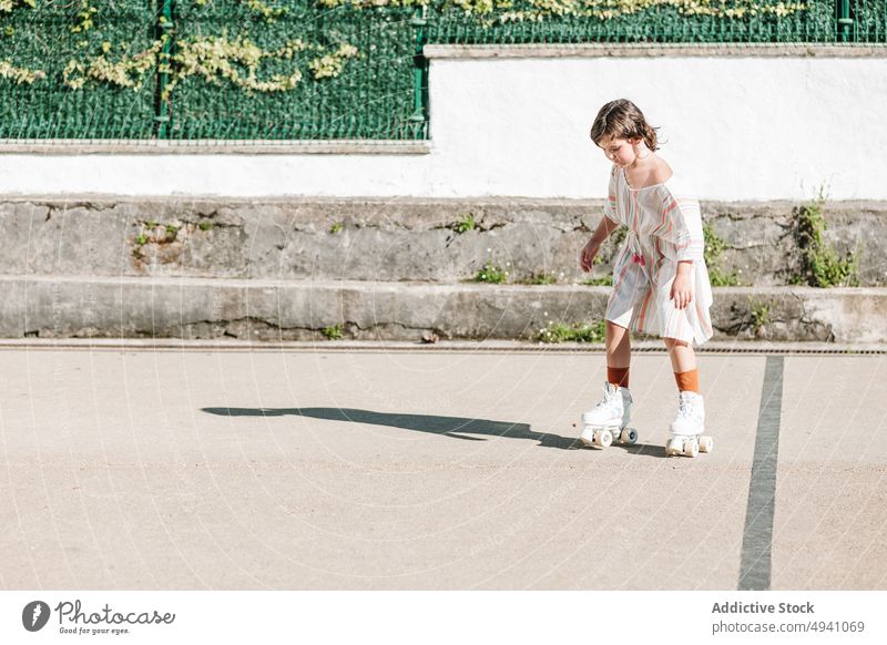 Focused girl riding roller skates on street ride summer weekend activity hobby urban kid pastime casual focus childhood free time concentrated practice