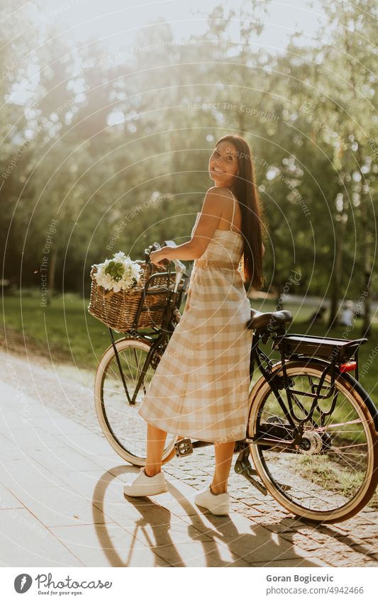 Young woman with flowers in the basket of electric bike active activity adult beautiful bicycle caucasian cycling day ebike exercise female flower basket