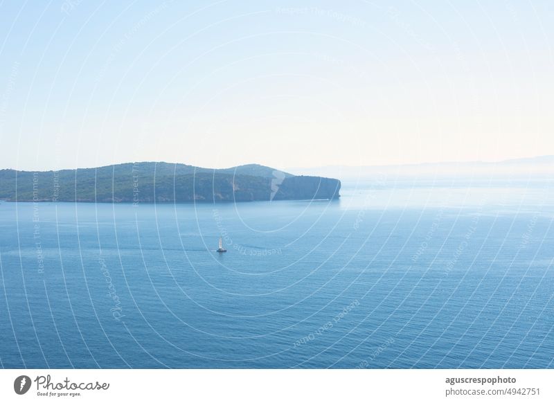 Sunny midday with a turquoise Mediterranean Sea on the horizon and a sailboat in the distance. Alghero Sassari Italy cape cacia sardinia top hill sunny