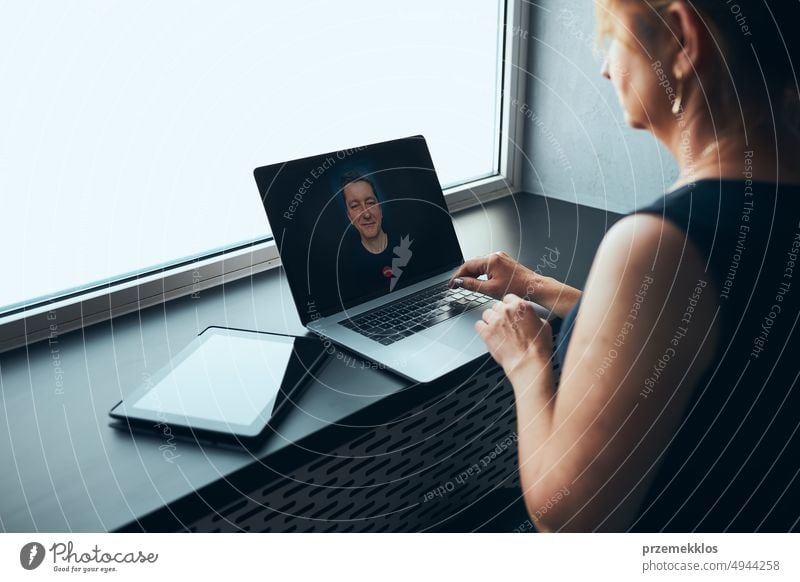 Businesswoman having business video call on laptop in office. Mature busy woman remotely working from office. Female manager using digital devices. Remote communication. Video calling. Remote work