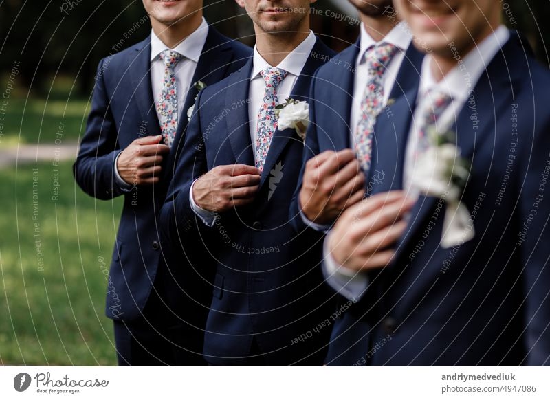 elegant groom's men with sttlish flowers tie. white Flowers in buttonhole, the groom's men are dressed in a dark suit. Wedding day. Outfit of the day.