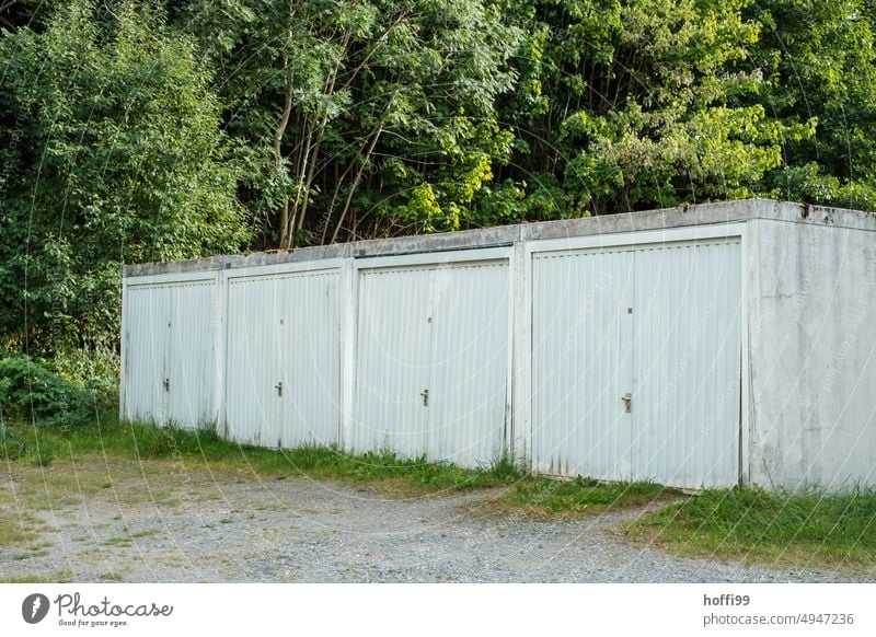 4 garages in a row surrounded by rampant greenery Garage Garage door Highway ramp (entrance) Highway ramp (exit) Row Row garage Town house (Terraced house)