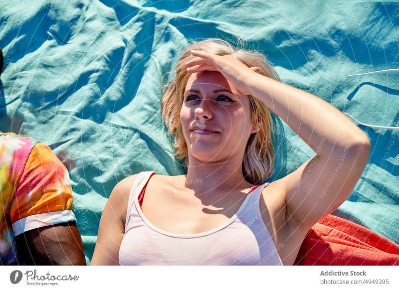 Woman looking at sky during picnic woman admire blanket friend touch forehead summer weekend rest sunny female boyfriend girlfriend couple date daytime glad