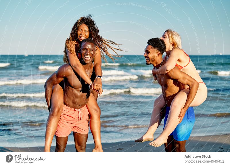 Diverse couple playing in waving sea wave beach happy summer weekend together relationship friend girlfriend boyfriend men women having fun multiracial diverse