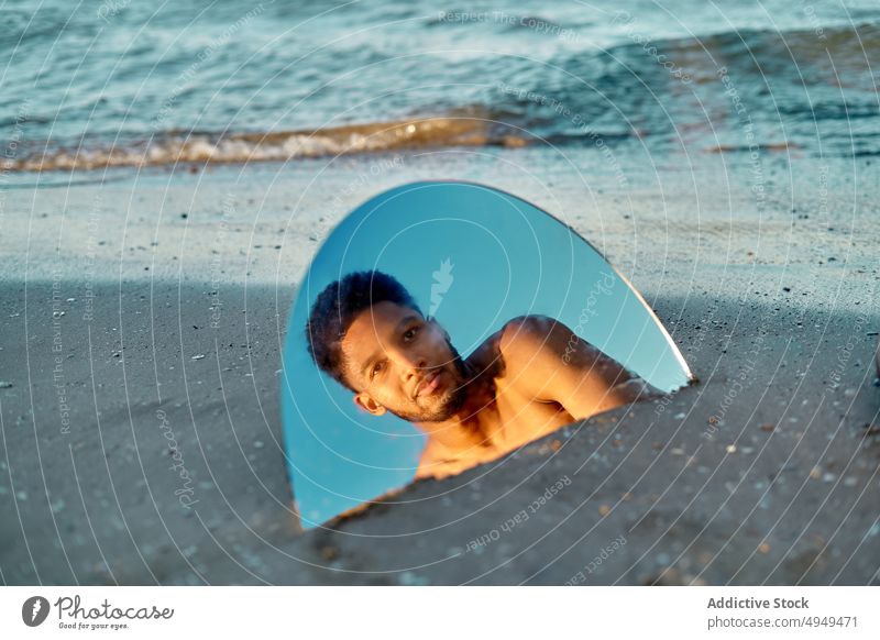 Black man with mirror near sea beach reflection summer weekend semicircle holiday resort male young black african american ethnic shirtless naked torso vacation