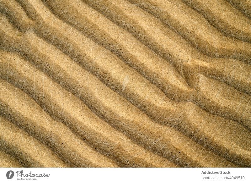 Rippling surface of dry sand ripple texture beach summer uneven rough background shore wave seaside desert climate arid drought brown barren terrain dune curve