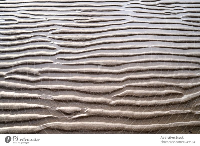 Rippling surface of dry sand ripple texture beach summer uneven rough background shore wave seaside desert climate arid drought brown barren terrain dune curve