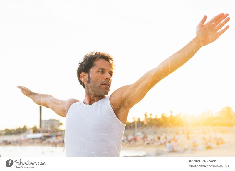 Man stretching body on beach in morning man twist yoga session sunrise practice summer male wellness balance energy coast vitality zen arms raised activity