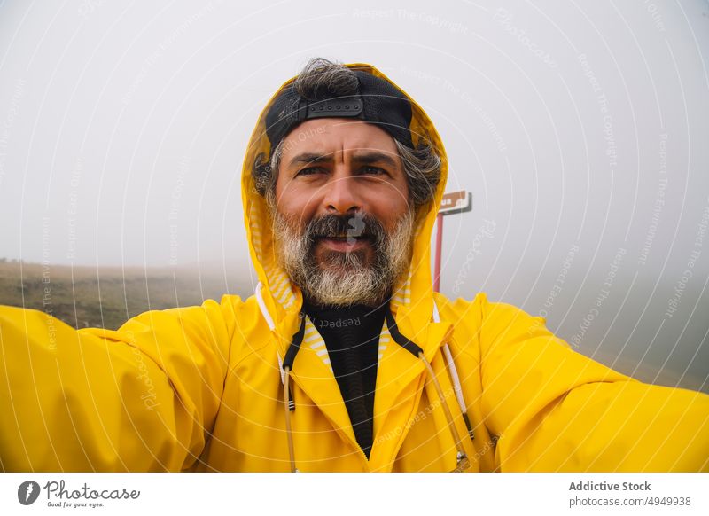 Middle aged man taking selfie in foggy morning traveler valley trip weekend nature raincoat self portrait irati navarre spain male mature middle age hiker beard