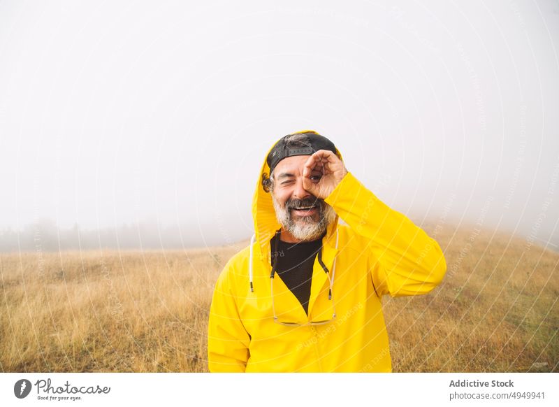 Mature male traveler in foggy valley man smile binocular gesture morning portrait happy irati navarre spain mist hike mature middle age cheerful explore nature