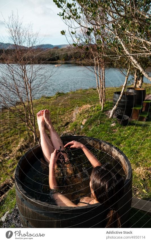 Female taking seaweed bath near lake woman rest barrel thoughtful shore calm spa resort female pensive young weekend water relax summer daytime quiet tranquil