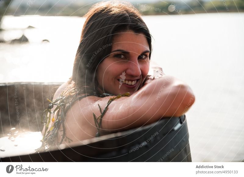 Happy brunette taking algae bath woman barrel hot seaweed smile spa lake shore portrait female resort bare shoulders positive weekend countryside summer