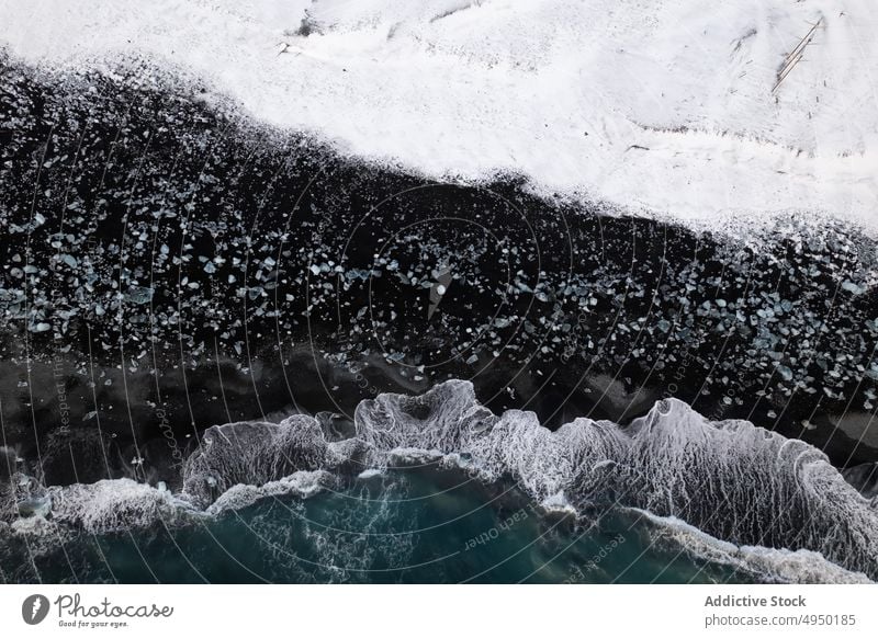 Sea waves rolling on snowy shore sea cold rock foam weather storm iceland coast splash water nature ocean rough climate stone frozen winter season terrain crash