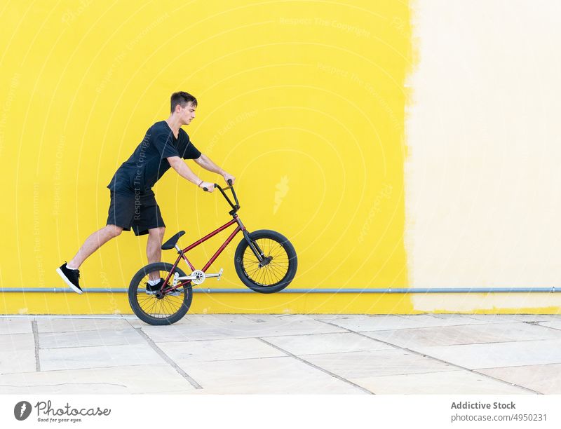 Man with BMX bike walking on wall man bmx trick street urban sidewalk hobby male bicyclist casual activity vehicle bicycle motion daytime pavement practice