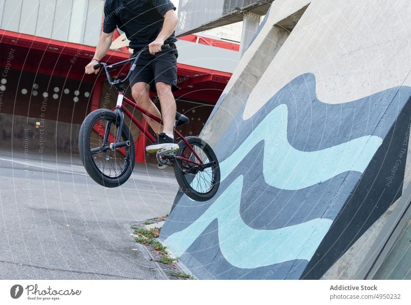 Anonymous man doing wallride trick on BMX bike bmx skate park urban street male young stunt energy practice cyclist hobby activity transport recreation move