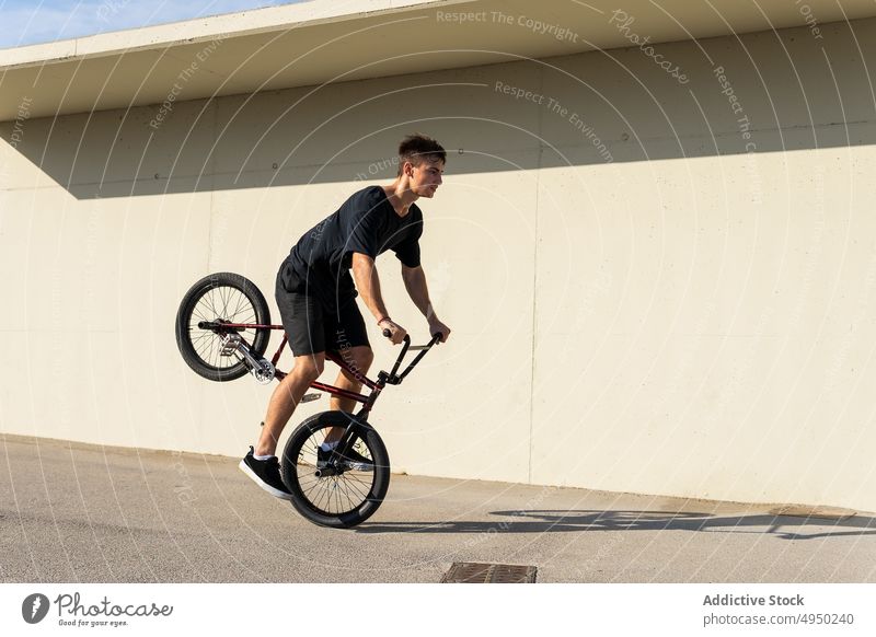 Man with BMX bike near on wall man bmx trick street urban sidewalk hobby male bicyclist casual activity vehicle bicycle motion daytime pavement practice balance